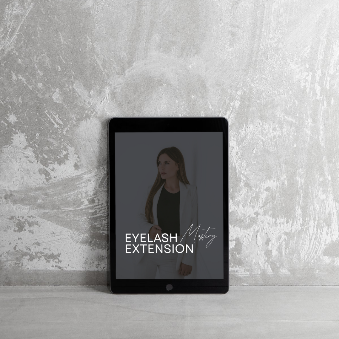 A tablet stands upright against a light grey textured wall, displaying an image of a woman in a white blazer and dark top. The screen reads EYELASH EXTENSION Mastery in white text.