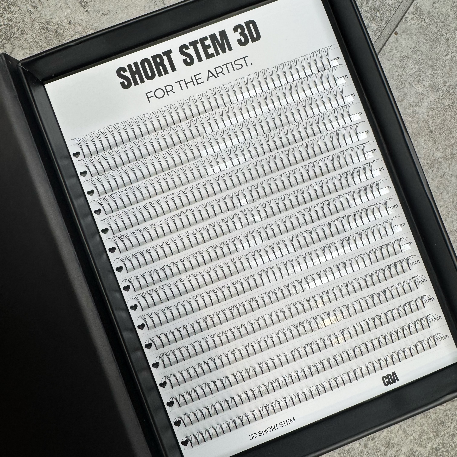 Eyelash extension tray labeled 'Short Stem 3D for the Artist' on a gray surface.