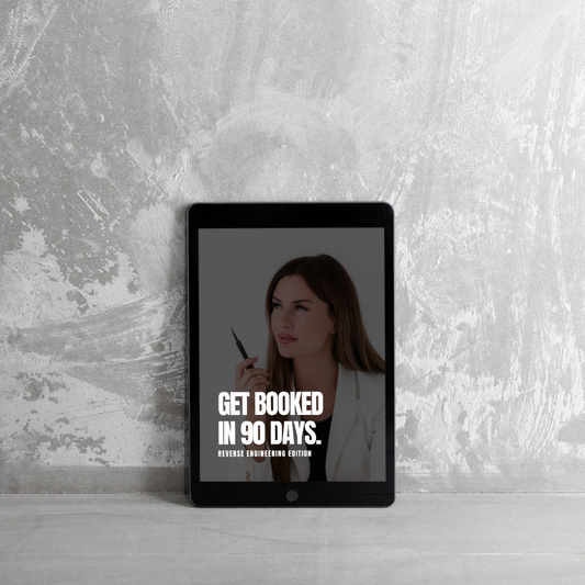 A tablet leaning against a textured gray wall displays an image of a woman holding a pen. Large white text on the screen reads, GET BOOKED IN 90 DAYS. REVERSE ENGINEERING EDITION.
